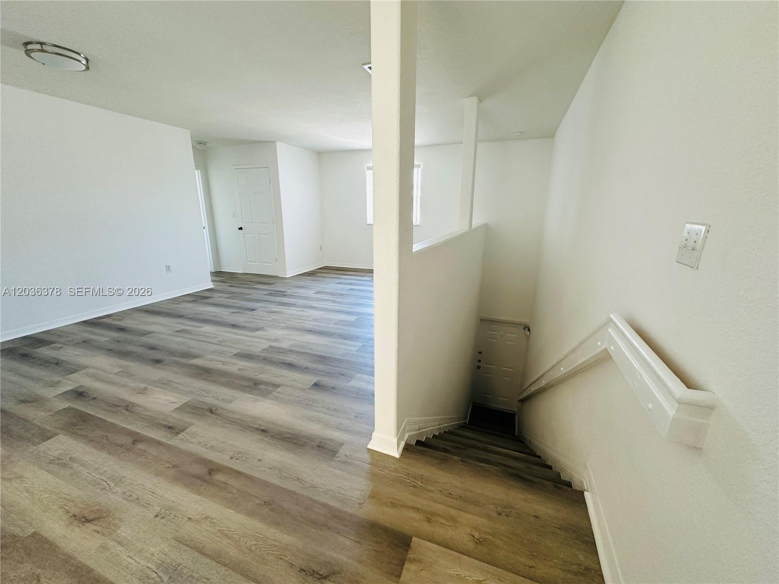 An interior view shows a room with wood-look flooring and stairs leading to a lower level — 5705 NW 109th Ave # 50, Doral FL 33178, DORAL, FL