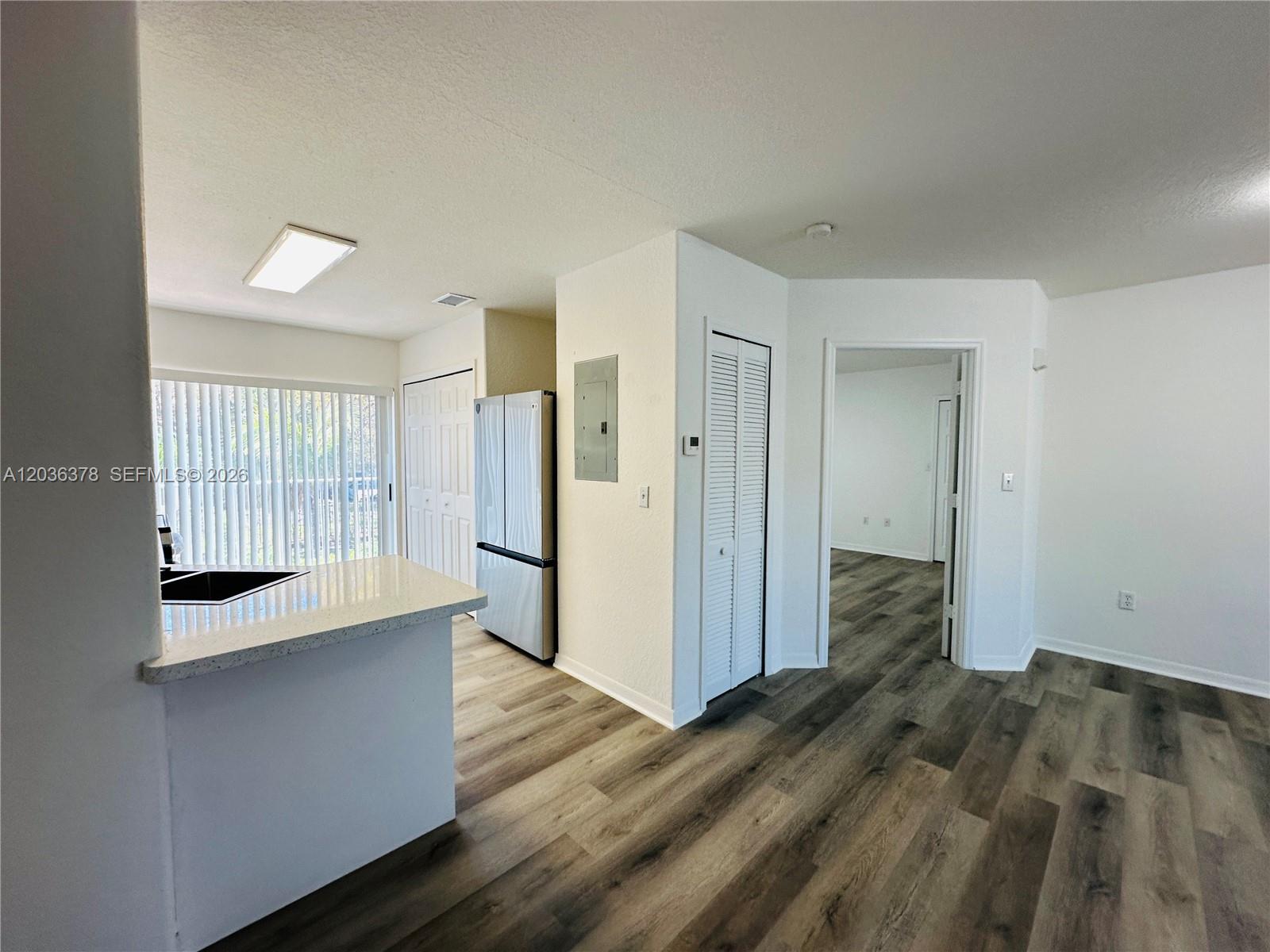 A kitchen with a breakfast bar, stainless steel refrigerator, and wood-look flooring — 5705 NW 109th Ave # 50, Doral FL 33178, DORAL, FL
