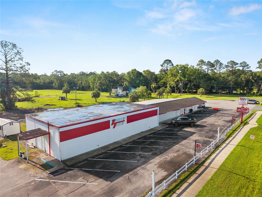 An aerial view shows a commercial building with a red and white exterior and parking — 17313 NE US HWY 301, WALDO, FL