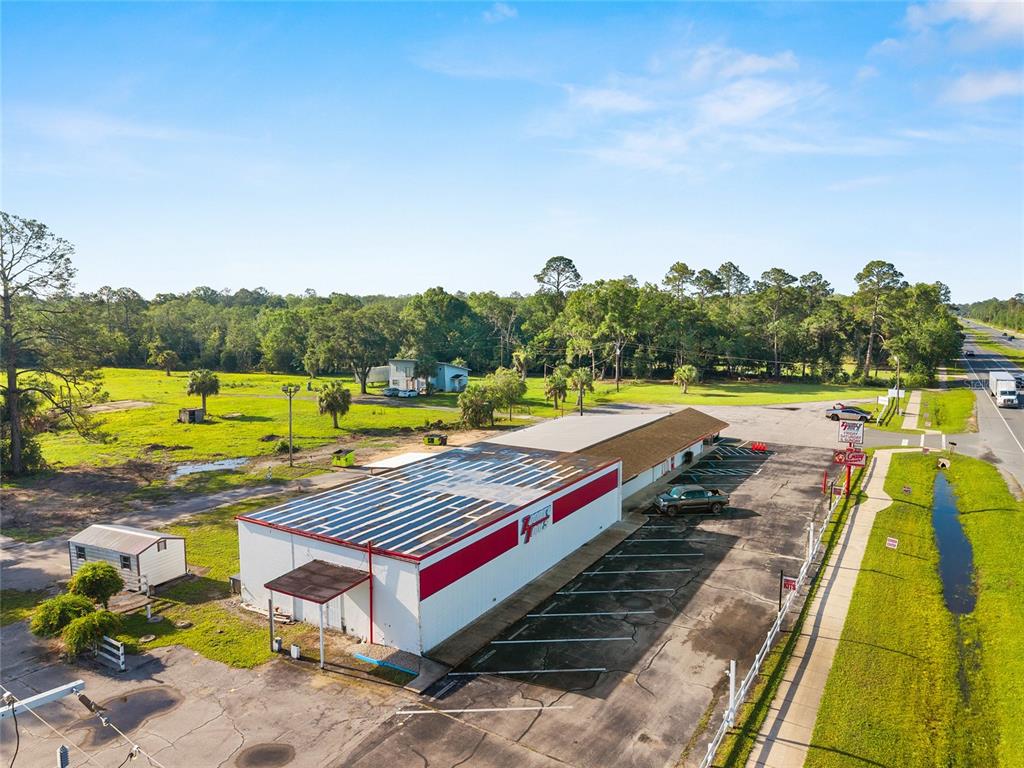 An aerial view shows a commercial building with a metal roof and adjacent parking lot — 17313 NE US HWY 301, WALDO, FL