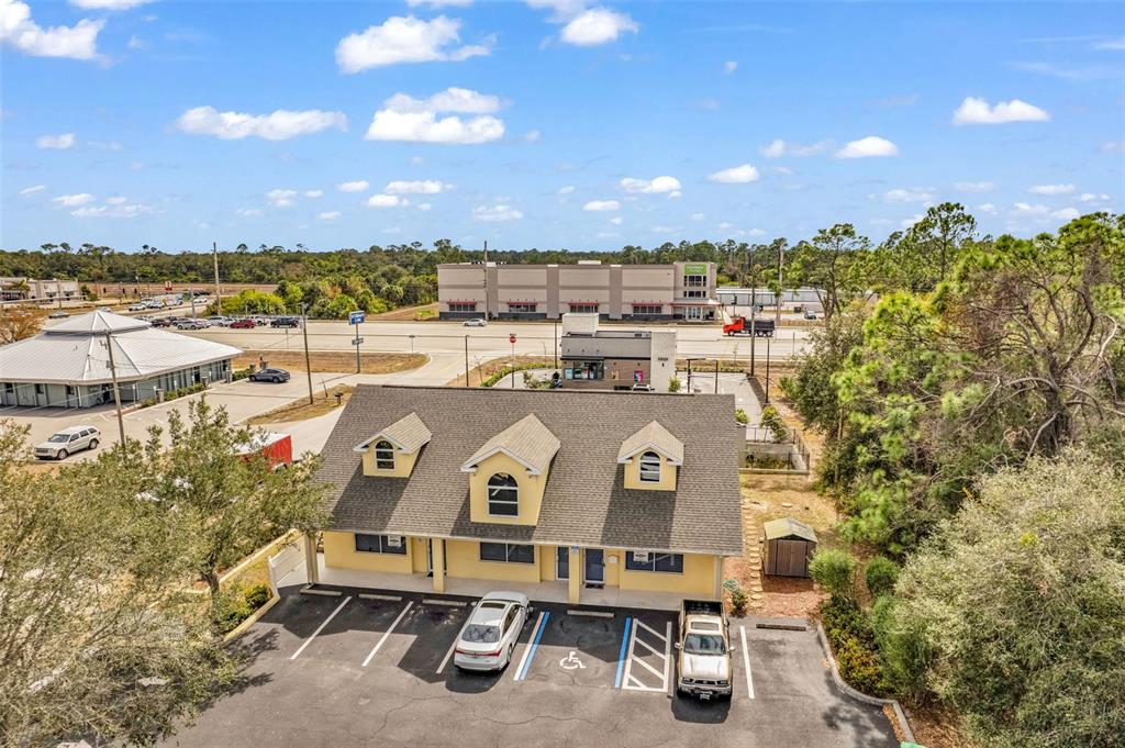 An aerial view shows a two-story yellow building with three dormers and a parking lot — 493 BARGER DRIVE, PORT CHARLOTTE, FL