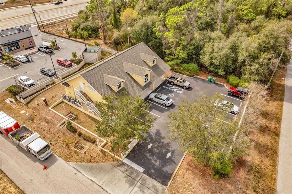 An aerial view shows a yellow commercial building with a parking lot and surrounding trees — 493 BARGER DRIVE, PORT CHARLOTTE, FL