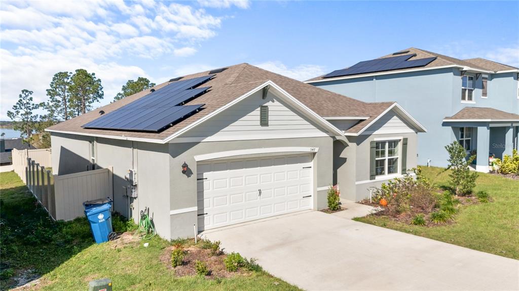 A single-story house with solar panels on the roof and a two-car garage — 547 TANARO LANE, HAINES CITY, FL