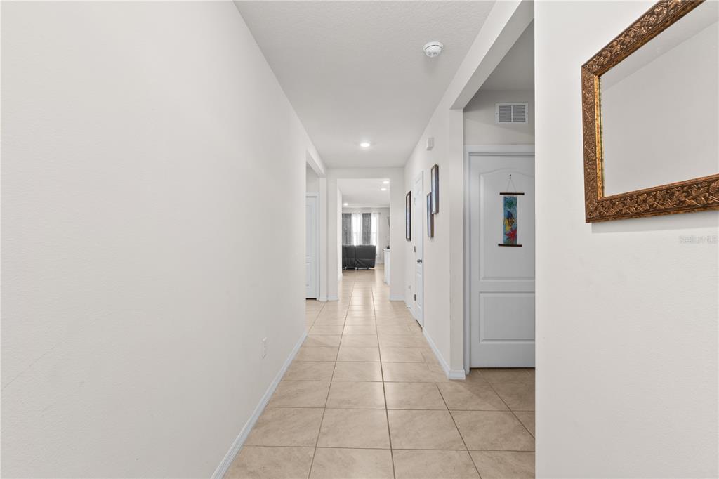 A long hallway with light-colored tile flooring leads toward a living area in the distance — 547 TANARO LANE, HAINES CITY, FL