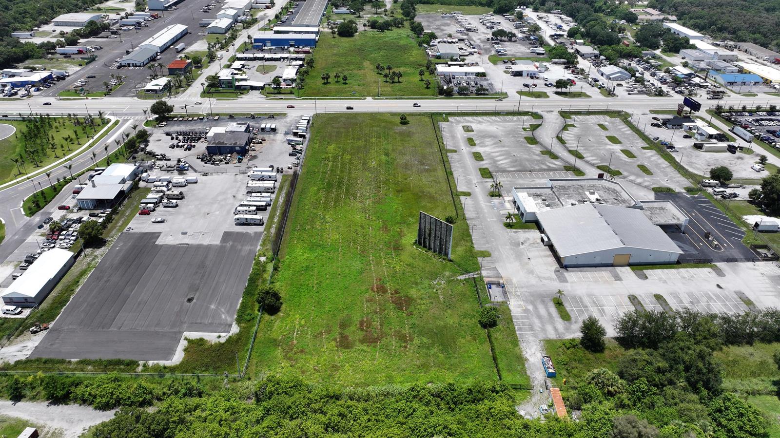 An aerial view shows a vacant grassy lot situated between two commercial properties and parking lots — 3450 S US Highway 1, Fort Pierce FL 34982, FORT PIERCE, FL