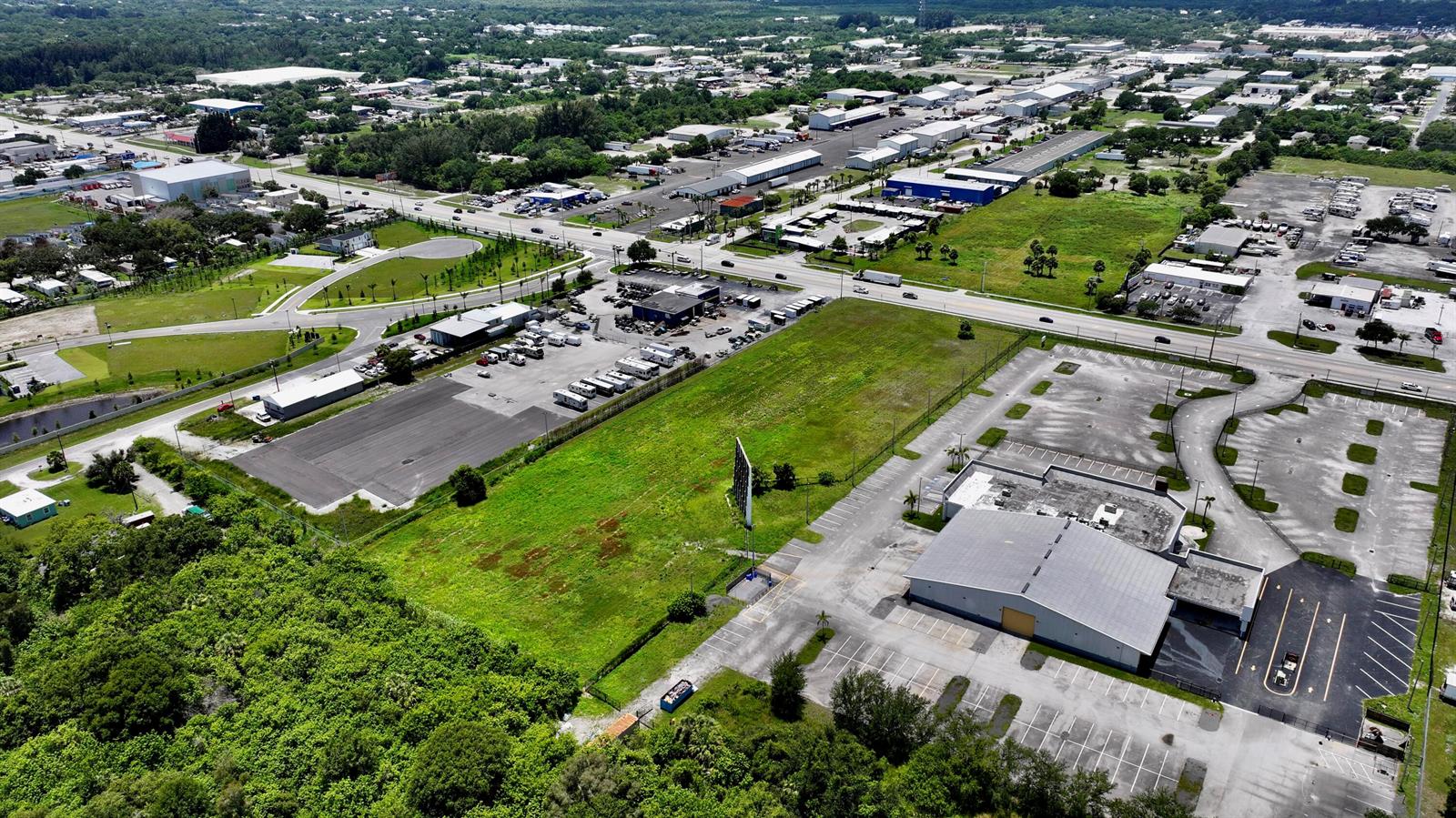 An aerial view shows a commercial property with a large building, parking lot, and field — 3450 S US Highway 1, Fort Pierce FL 34982, FORT PIERCE, FL