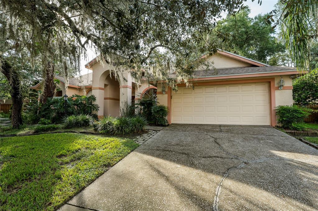 A single-story house with a beige stucco exterior, a two-car garage, and a concrete driveway — 1336 WATERWOOD DRIVE, LUTZ, FL