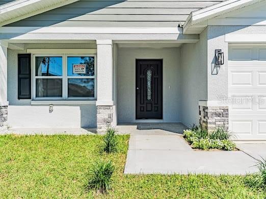 The exterior of a house features a front door, a window, and a garage — 102 SAIL WAY, KISSIMMEE, FL
