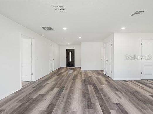An interior view of a room with white walls, light-colored wood-look flooring, and multiple doors — 102 SAIL WAY, KISSIMMEE, FL