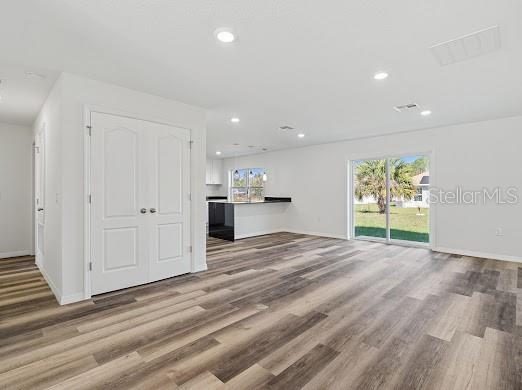 An open-concept living area features wood-look flooring, white walls, double closet doors, and a kitchen — 102 SAIL WAY, KISSIMMEE, FL