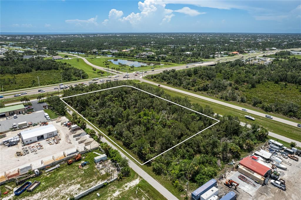 An aerial view shows a rectangular, tree-covered vacant lot bordered by roads and commercial properties — 13440 MARATHON BOULEVARD, PORT CHARLOTTE, FL