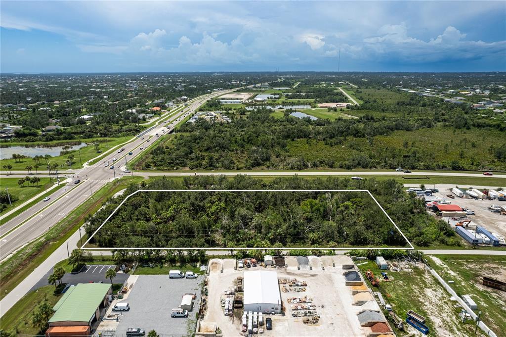 An aerial view shows a rectangular, wooded vacant lot bordered by roads and commercial properties — 13440 MARATHON BOULEVARD, PORT CHARLOTTE, FL
