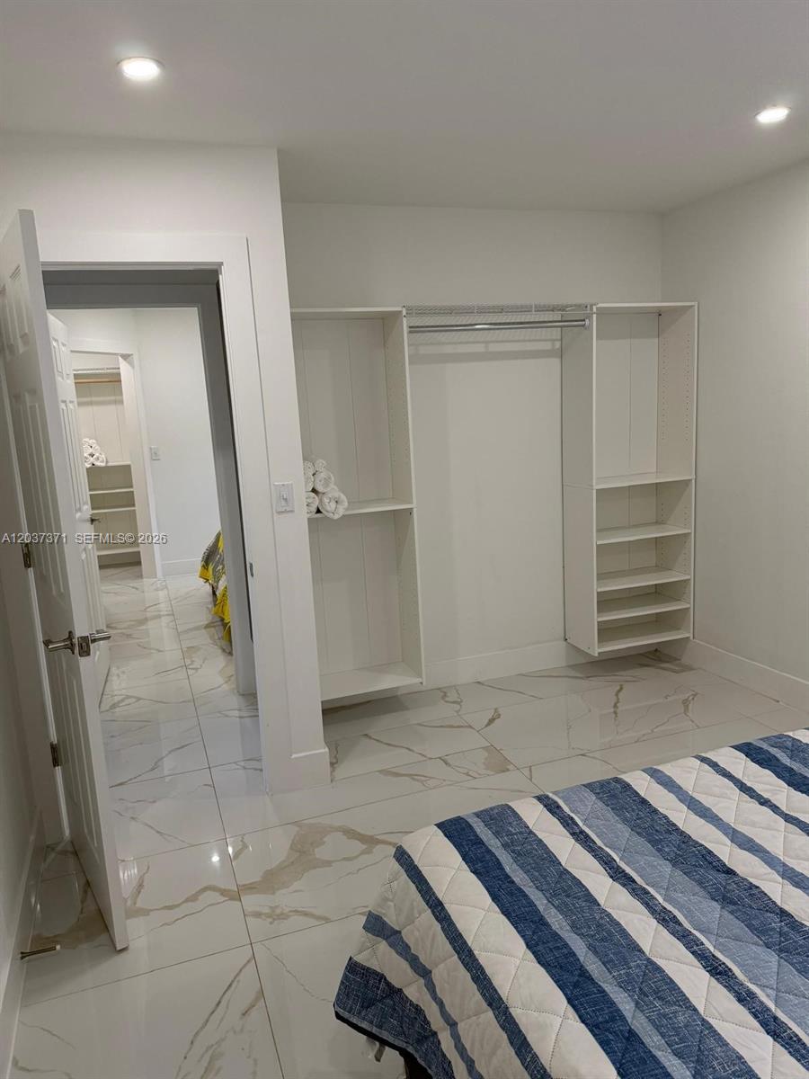 A bedroom features white walls, marble-look tile flooring, and an open closet system — 208 NW 7th St # 1, Hallandale Beach FL 33009, HALLANDALE BEACH, FL