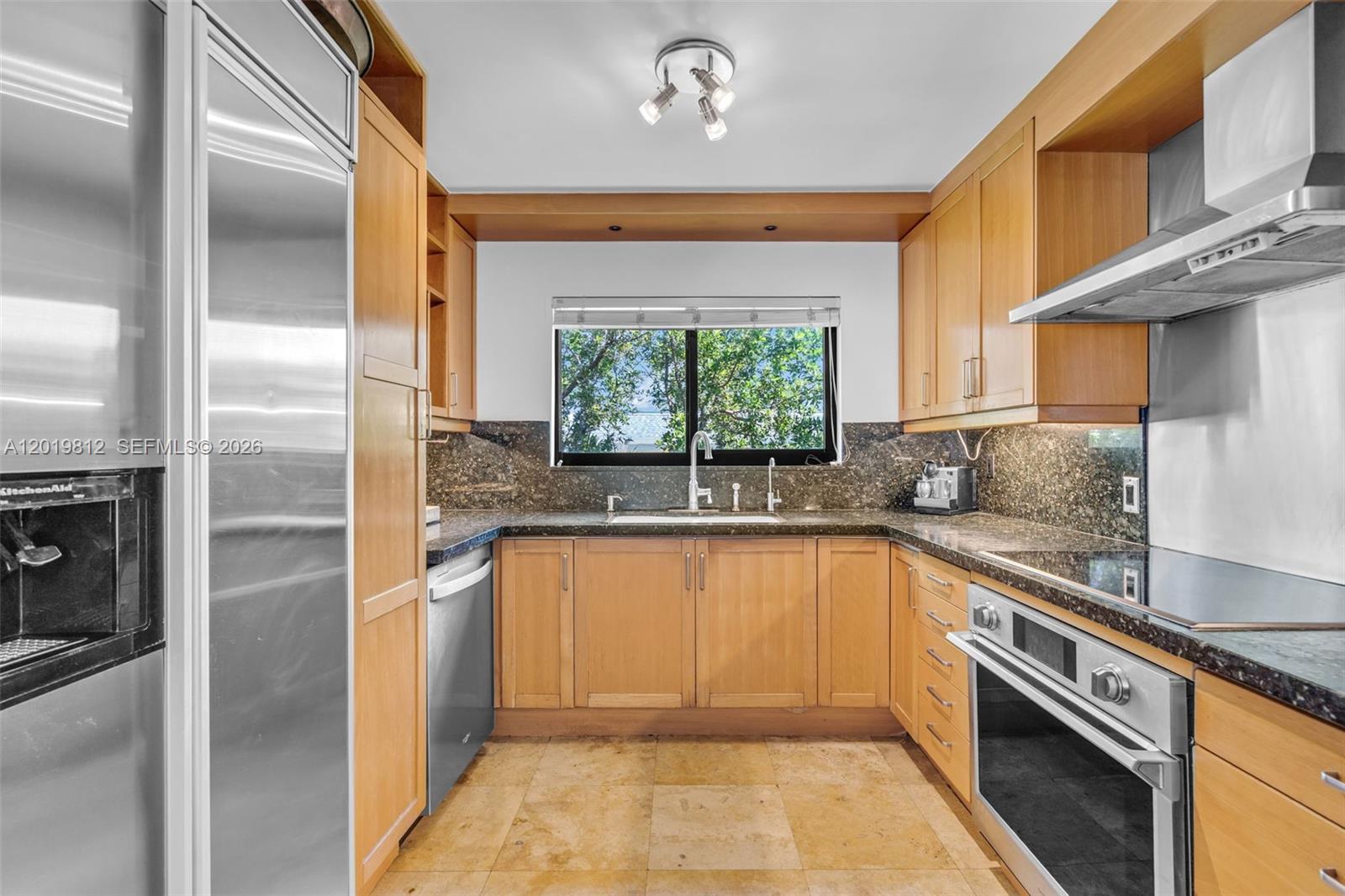 A galley kitchen features light wood cabinets, dark granite countertops, and stainless steel appliances — 209 E Enid Dr # 36, Key Biscayne FL 33149, KEY BISCAYNE, FL