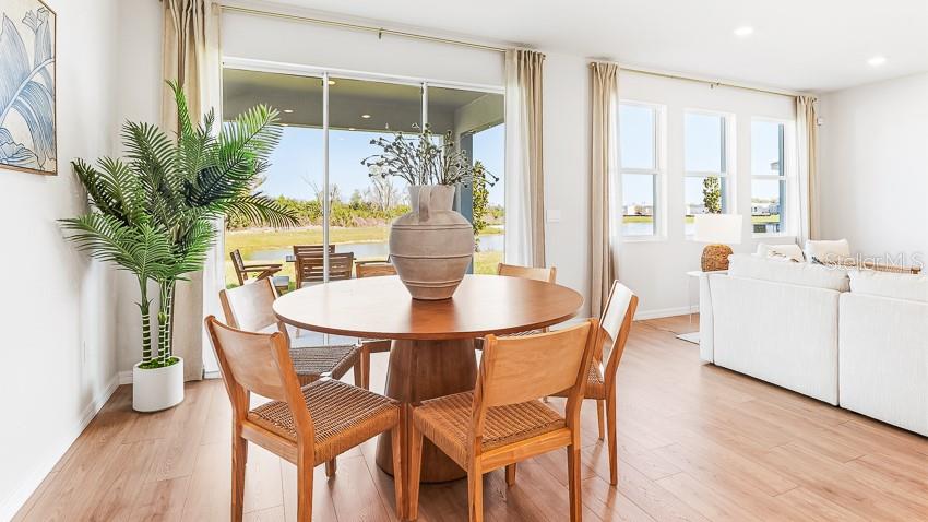 A dining area with a round wooden table and chairs sits before a sliding glass door — 18217 GANDER TERRACE, LAKEWOOD RANCH, FL