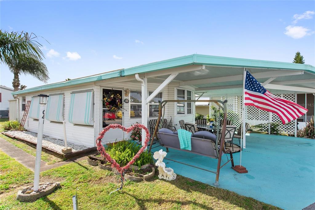 A mobile home exterior features a turquoise-painted carport, a porch swing, and a heart-shaped decoration — 251 PATTERSON ROAD UNIT C-41, HAINES CITY, FL