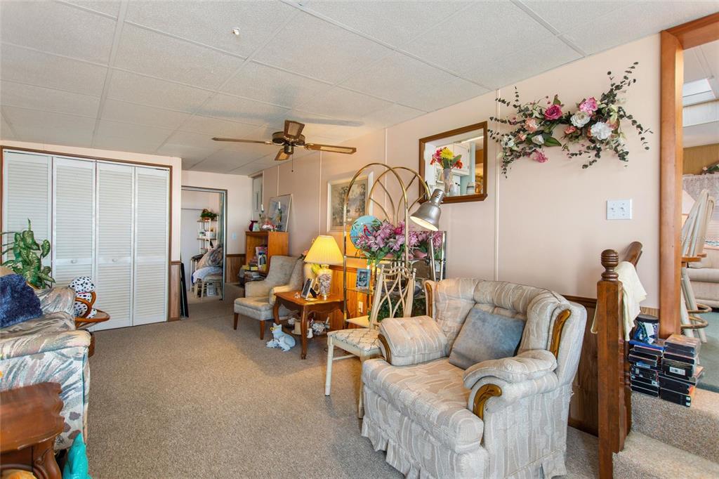 A living room with carpeted floors, a ceiling fan, and floral wall decor — 251 PATTERSON ROAD UNIT C-41, HAINES CITY, FL