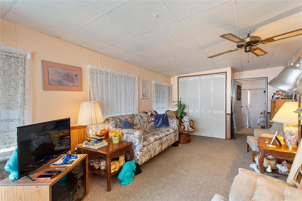A living room with beige walls, a floral sofa, a ceiling fan, and carpeted flooring — 251 PATTERSON ROAD UNIT C-41, HAINES CITY, FL