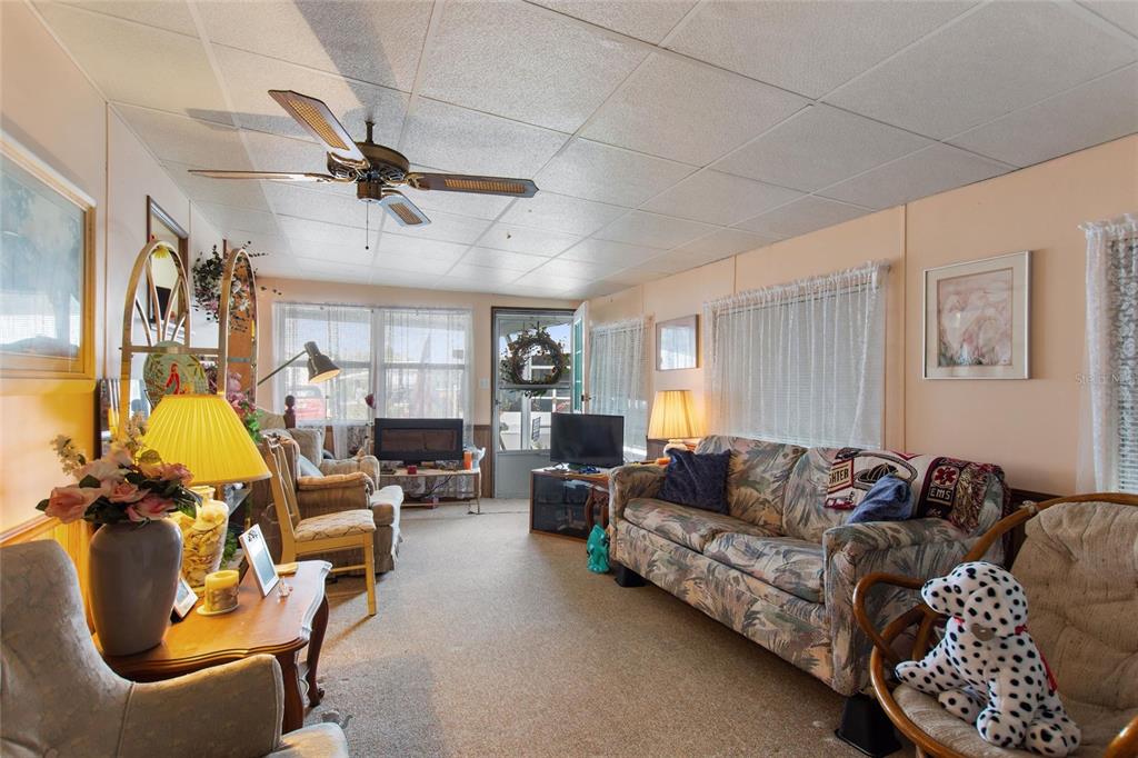 A living room features a ceiling fan, carpeted floors, a patterned sofa, and a doorway — 251 PATTERSON ROAD UNIT C-41, HAINES CITY, FL