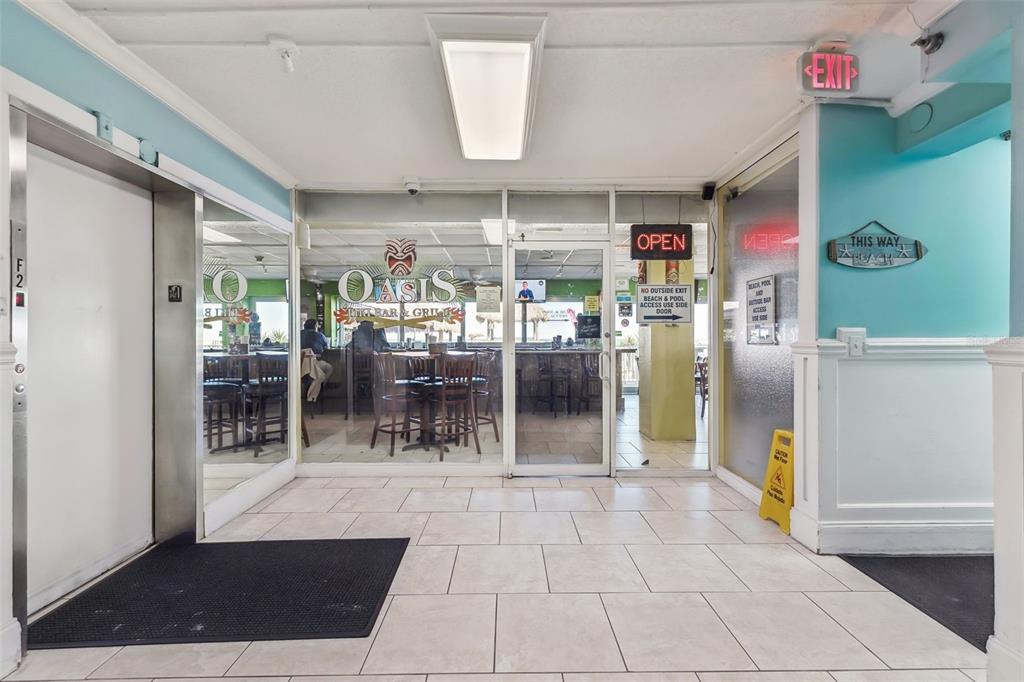 A tiled hallway leads to the glass-fronted Oasis Bar & Grill with an elevator nearby — 313 S ATLANTIC AVENUE UNIT 2090, DAYTONA BEACH, FL
