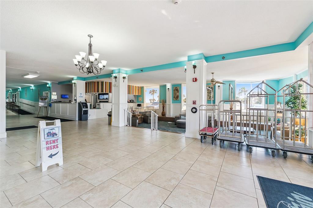 A hotel lobby features tiled floors, a chandelier, a reception desk, and luggage carts — 313 S ATLANTIC AVENUE UNIT 2090, DAYTONA BEACH, FL