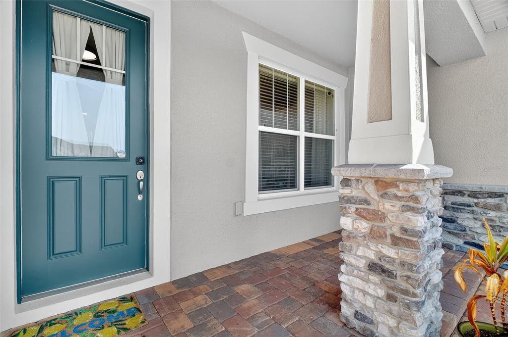 A teal front door sits next to a window and a stone-based porch column — 3222 FIDDLEWOOD CT, CLERMONT, FL