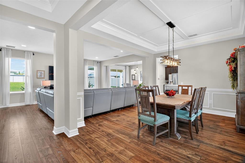 A dining area with a wooden table and chairs opens into a living room — 3222 FIDDLEWOOD CT, CLERMONT, FL
