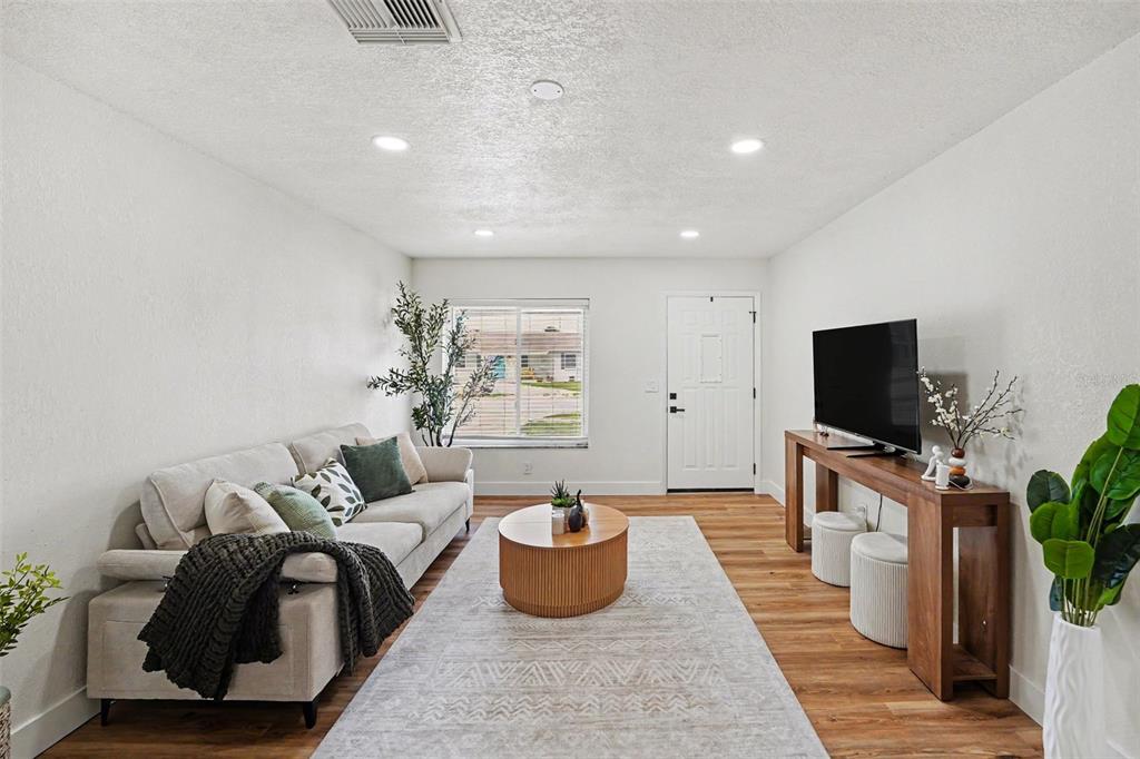 A living room with wood-look flooring, a television console, and an adjacent dining area — 9036 109TH TERRACE, SEMINOLE, FL