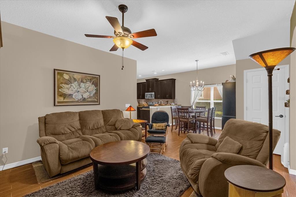 A living room with brown furniture, a ceiling fan, and an open view of the kitchen — 1355 ALSTON BAY BOULEVARD, APOPKA, FL