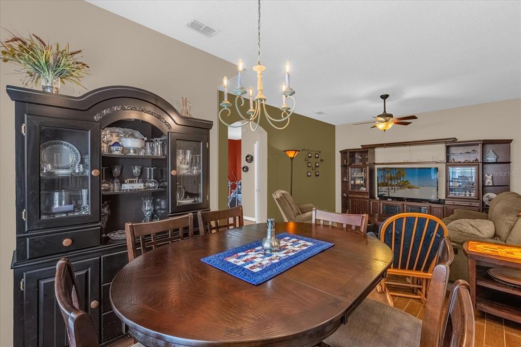A dining area with a wooden table and hutch opens into a living room space — 1355 ALSTON BAY BOULEVARD, APOPKA, FL