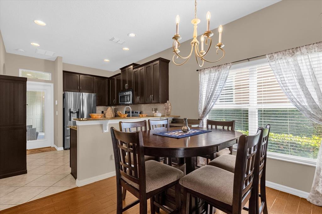 A dining area with a wooden table and chairs sits adjacent to a dark-cabinet kitchen — 1355 ALSTON BAY BOULEVARD, APOPKA, FL