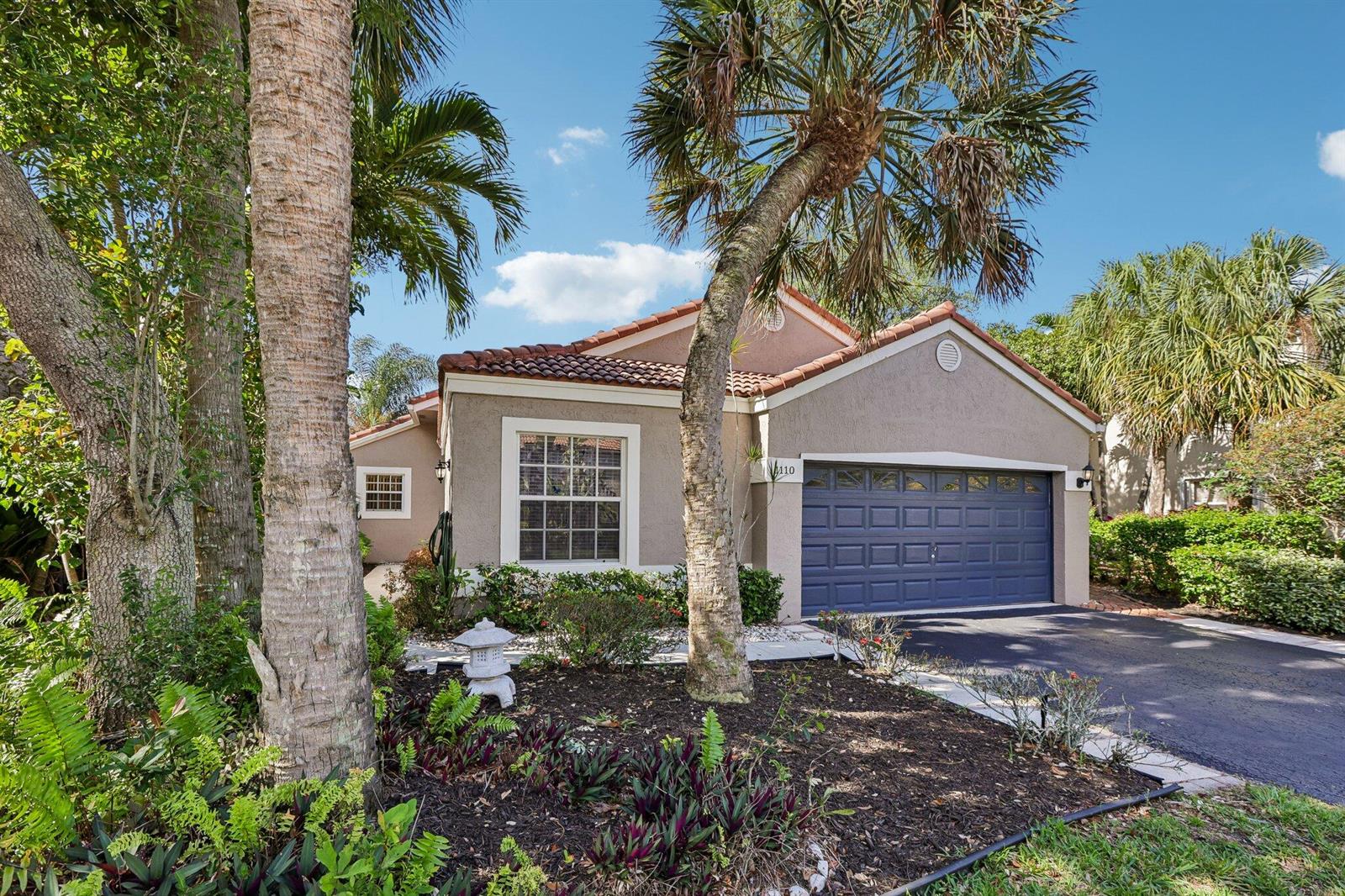 A single-story house with a blue garage door, stucco exterior, and palm trees in front — 1110 NW 105th Way, Plantation FL 33322, PLANTATION, FL