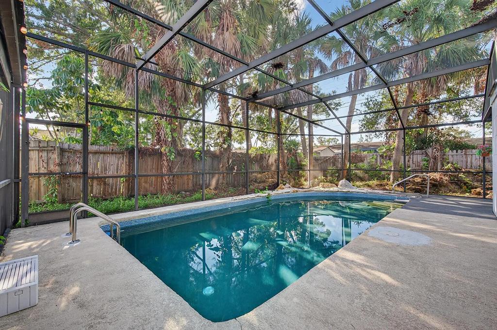 A sunroom features a stone accent wall, light wood-look flooring, an aquarium, and indoor planters — 7990 42ND STREET N, PINELLAS PARK, FL