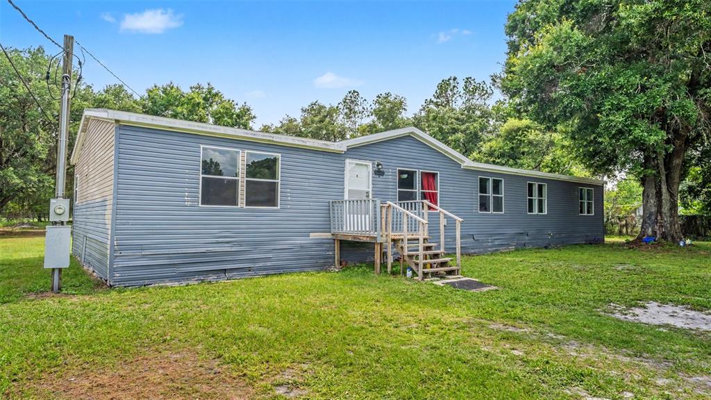 A single-story blue mobile home with a wooden front porch sits on a grassy lot — 4736 WALNUT CIRCLE S, LAKELAND, FL