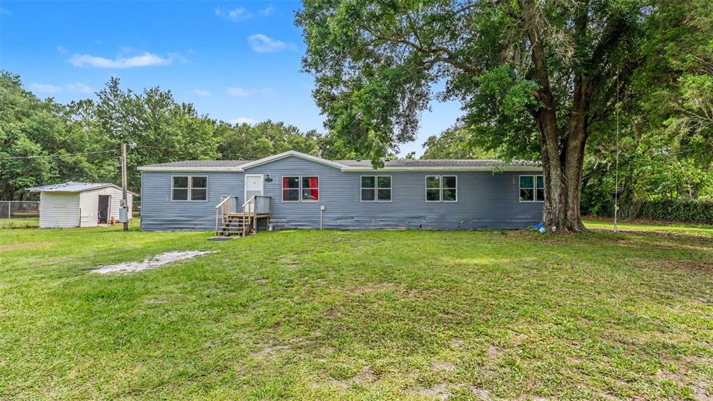 A blue single-wide mobile home with a small wooden porch sits on a grassy lot — 4736 WALNUT CIRCLE S, LAKELAND, FL
