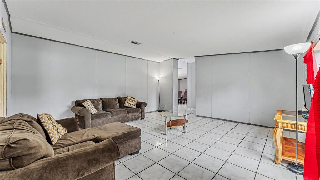 A living room features light gray walls, white tile flooring, and two brown fabric sofas — 4736 WALNUT CIRCLE S, LAKELAND, FL