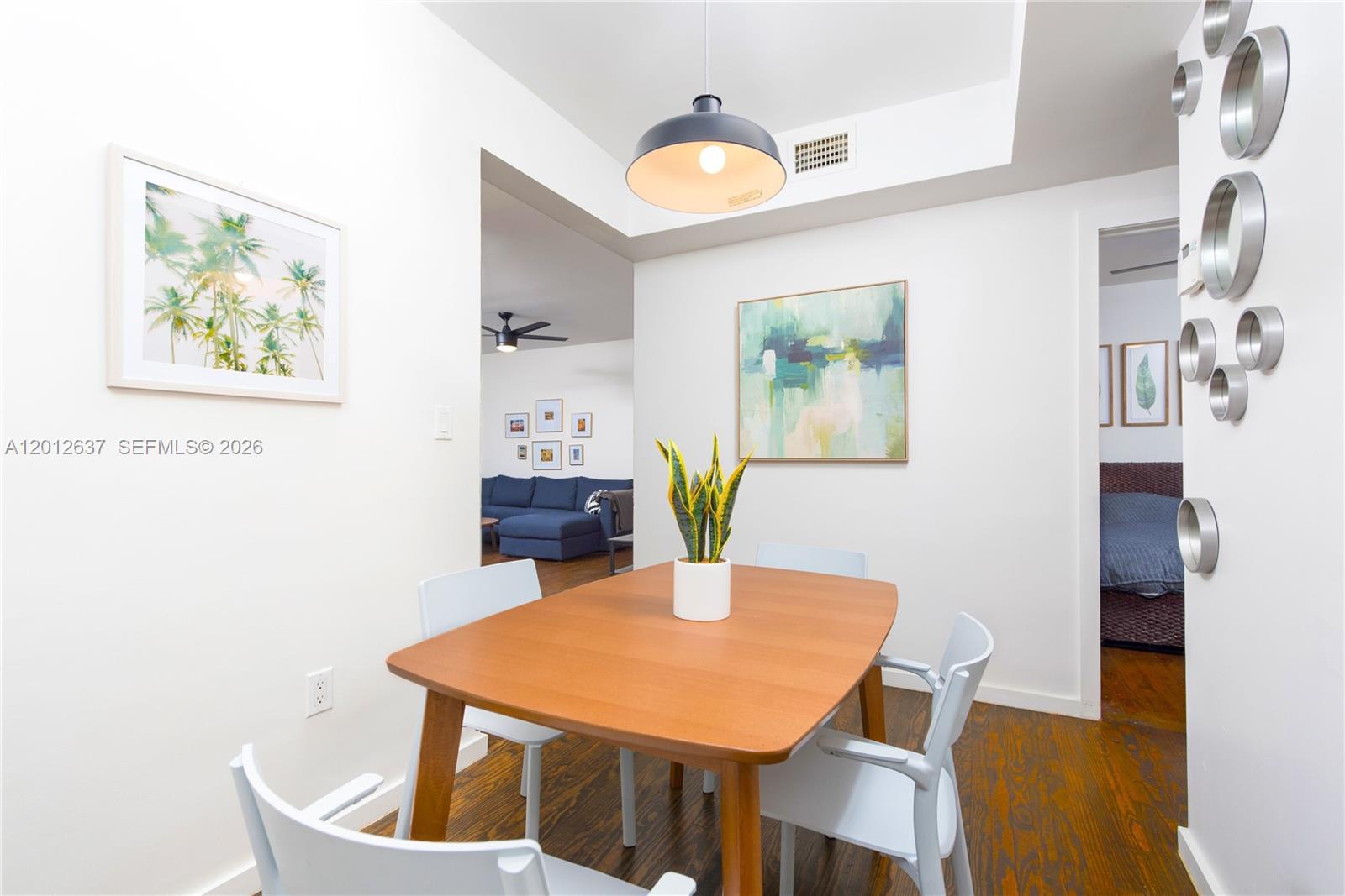 A dining area features a wooden table, white chairs, and wall art on hardwood floors — 1616 Euclid Ave # 7, Miami Beach FL 33139, MIAMI BEACH, FL