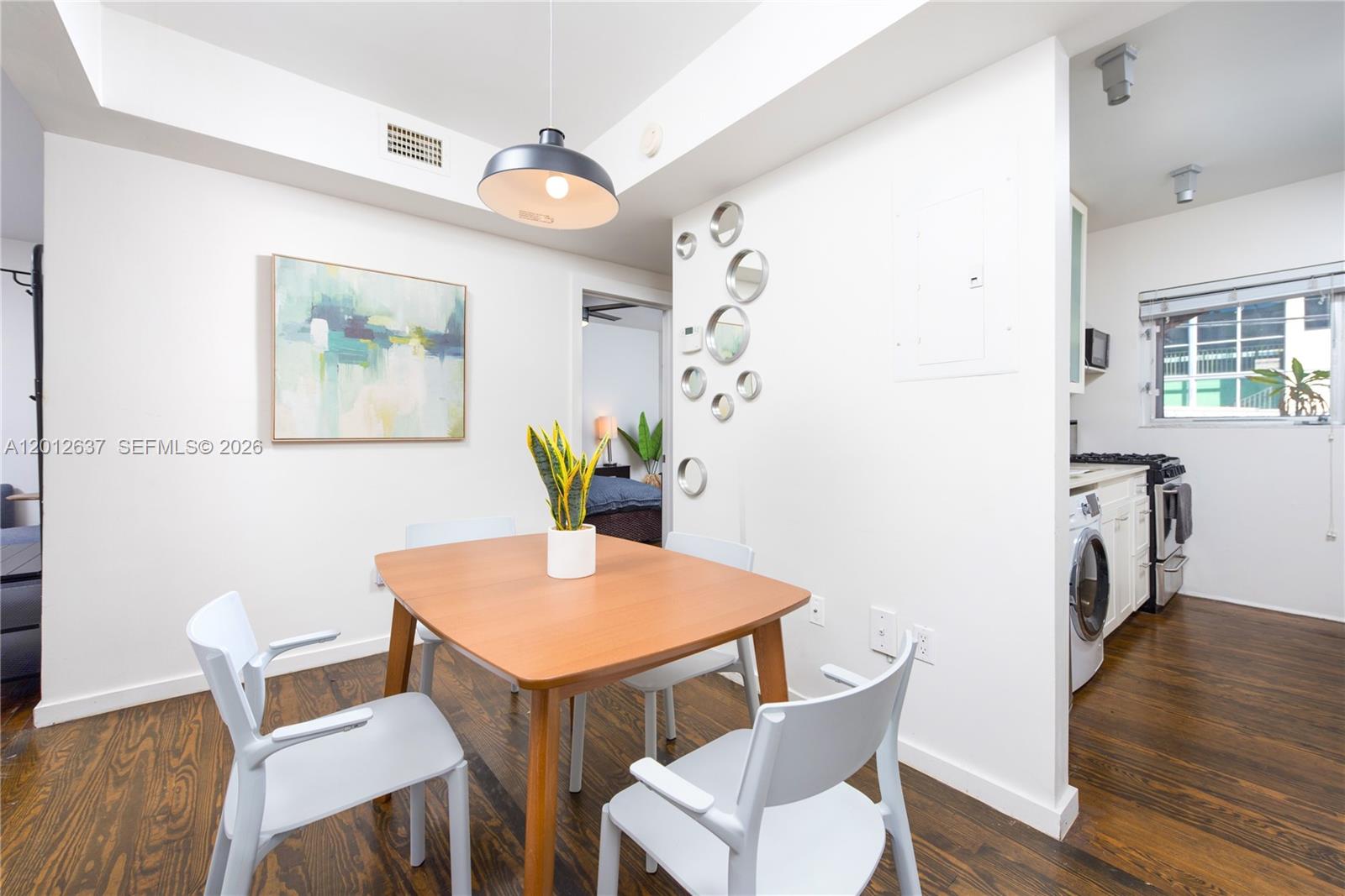A dining area features a wooden table, four chairs, and a wall decorated with circular mirrors — 1616 Euclid Ave # 7, Miami Beach FL 33139, MIAMI BEACH, FL