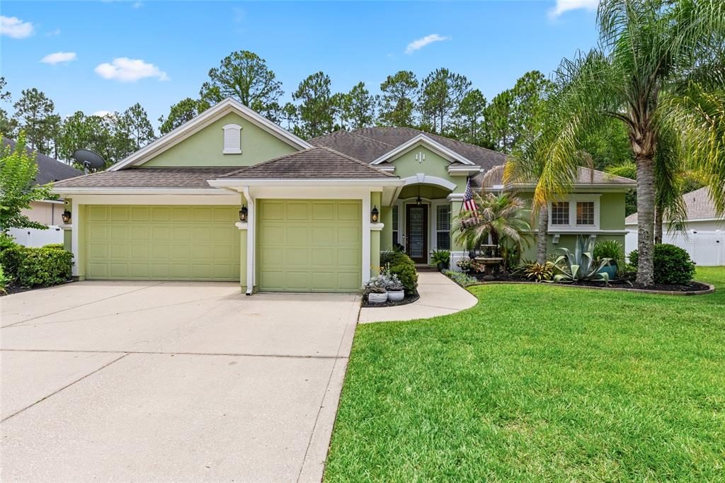 A single-story house with a green exterior, a three-car garage, and a landscaped front yard — 245 WORTHINGTON PARKWAY, ST JOHNS, FL