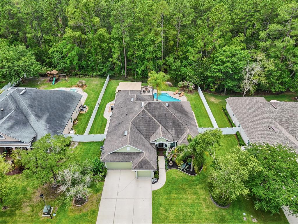 An aerial view shows a suburban house with a pool, backyard, and surrounding wooded area — 245 WORTHINGTON PARKWAY, ST JOHNS, FL