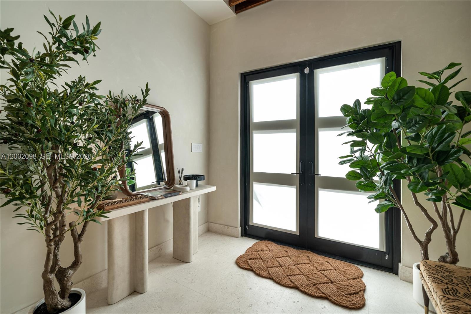 An entryway features a console table, a mirror, two potted plants, and double glass doors — 1735 Michigan Ave, Miami Beach FL 33139, MIAMI BEACH, FL