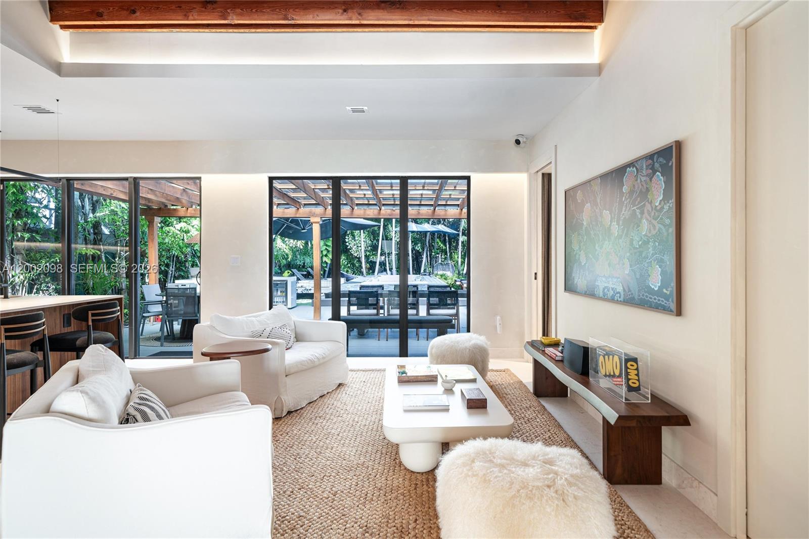 A living room with white armchairs, a coffee table, and sliding glass doors to a patio — 1735 Michigan Ave, Miami Beach FL 33139, MIAMI BEACH, FL