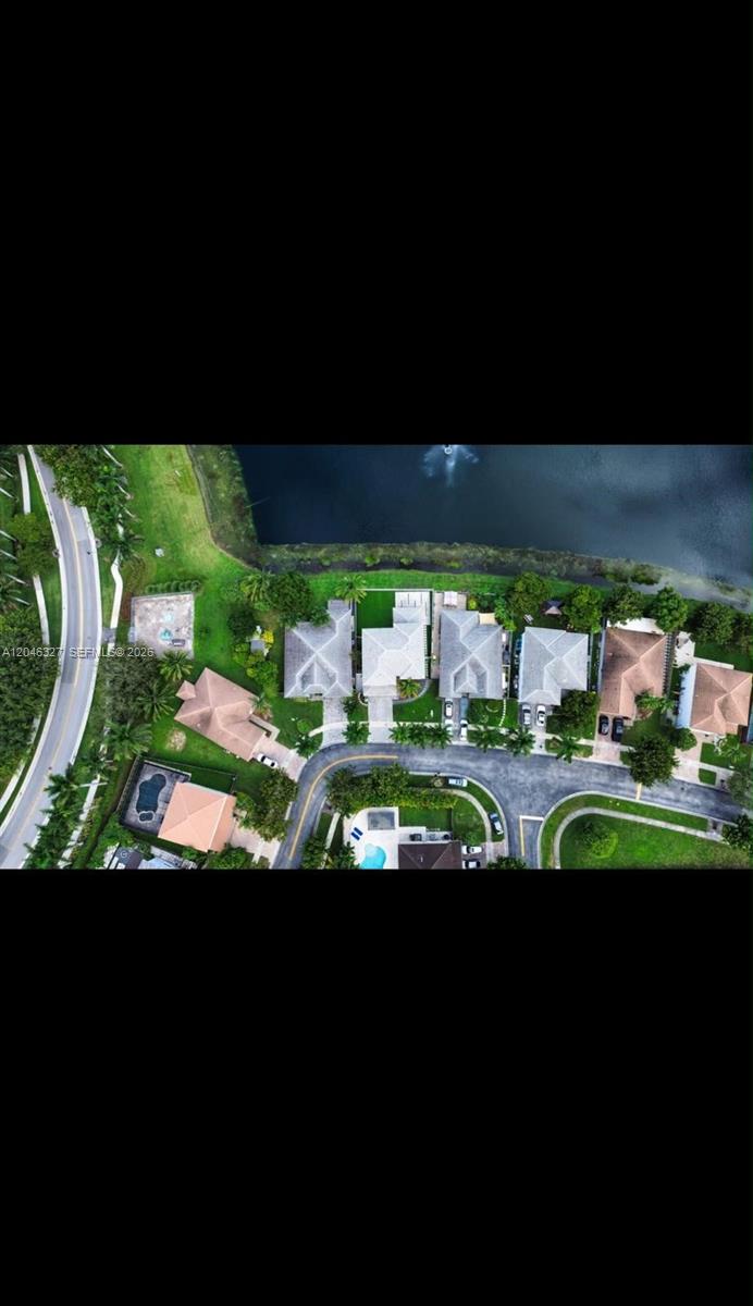 An aerial view shows a row of suburban houses situated along a curved road and lake — 449 SE 31st Ave, Homestead FL 33033, HOMESTEAD, FL