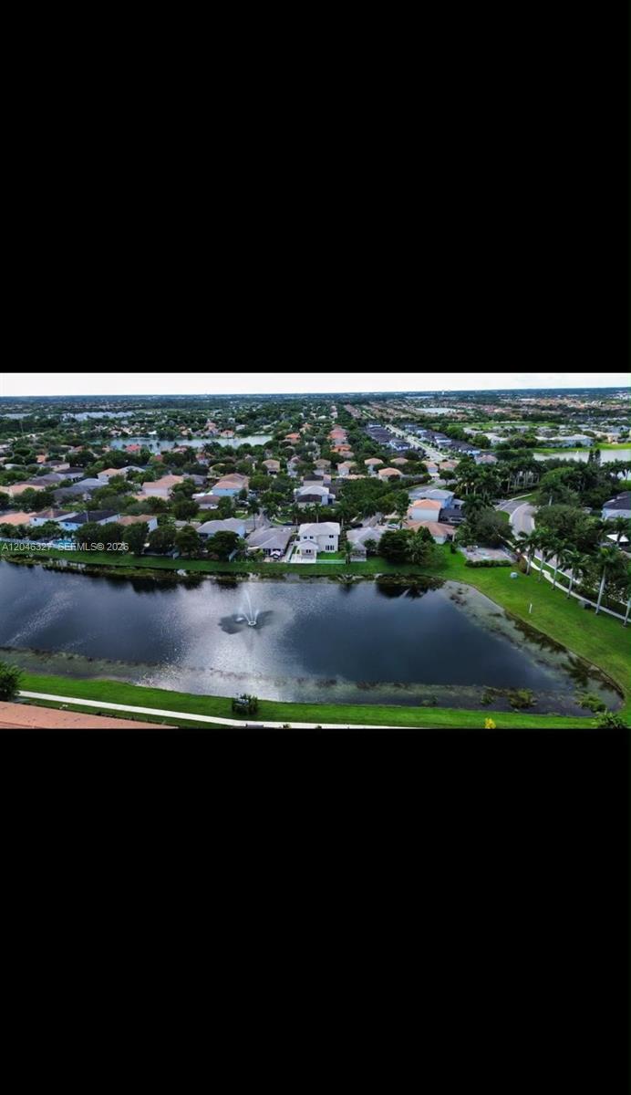 An aerial view shows a suburban neighborhood with houses surrounding a lake with a fountain — 449 SE 31st Ave, Homestead FL 33033, HOMESTEAD, FL