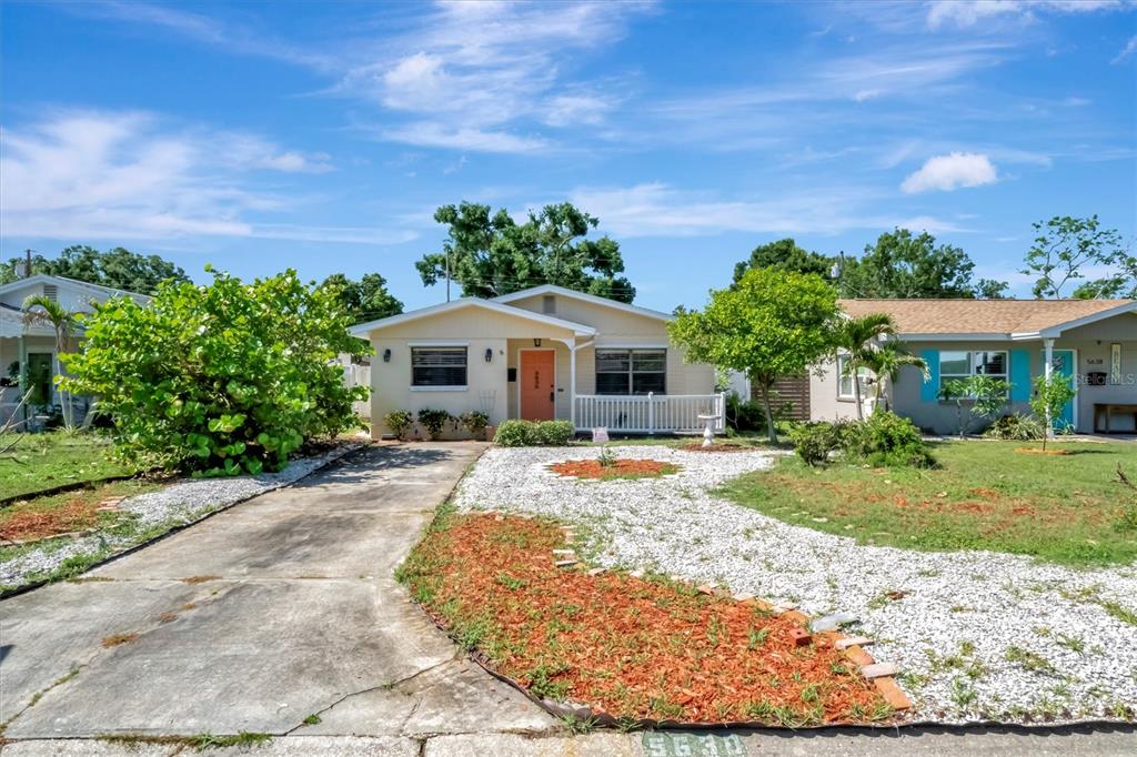 A single-story house with a concrete driveway, a peach front door, and a gravel yard — 5630 13TH AVENUE N, ST PETERSBURG, FL