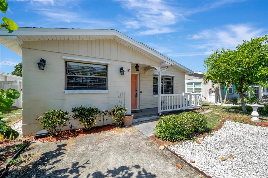 A single-story house with beige siding, a front porch, and a gravel driveway — 5630 13TH AVENUE N, ST PETERSBURG, FL