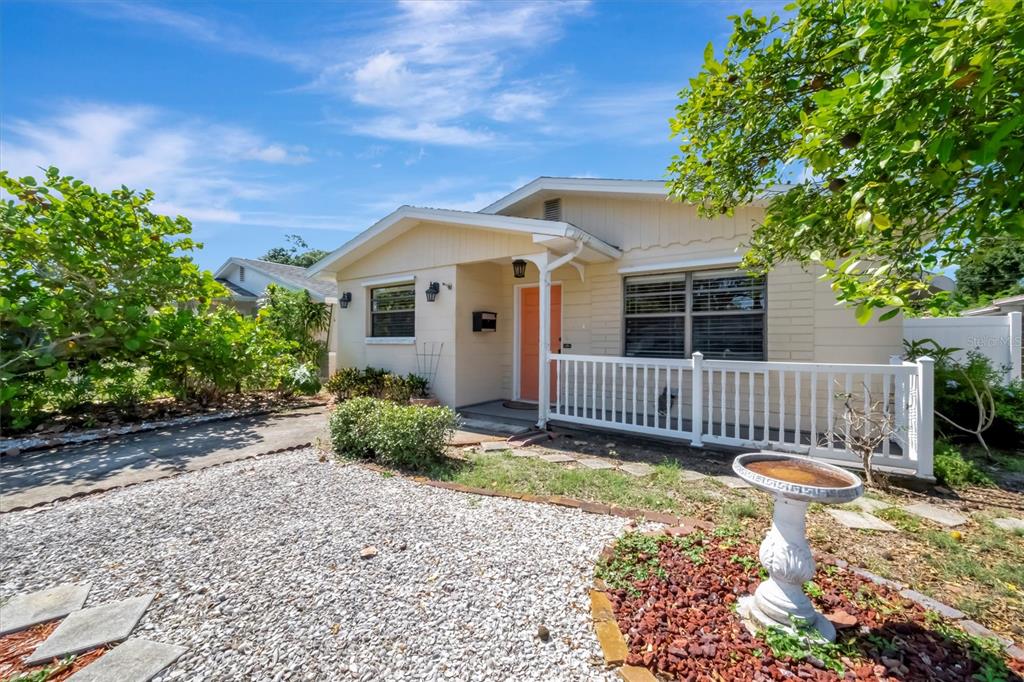 A single-story house with a light-colored exterior, a peach front door, and a gravel yard — 5630 13TH AVENUE N, ST PETERSBURG, FL
