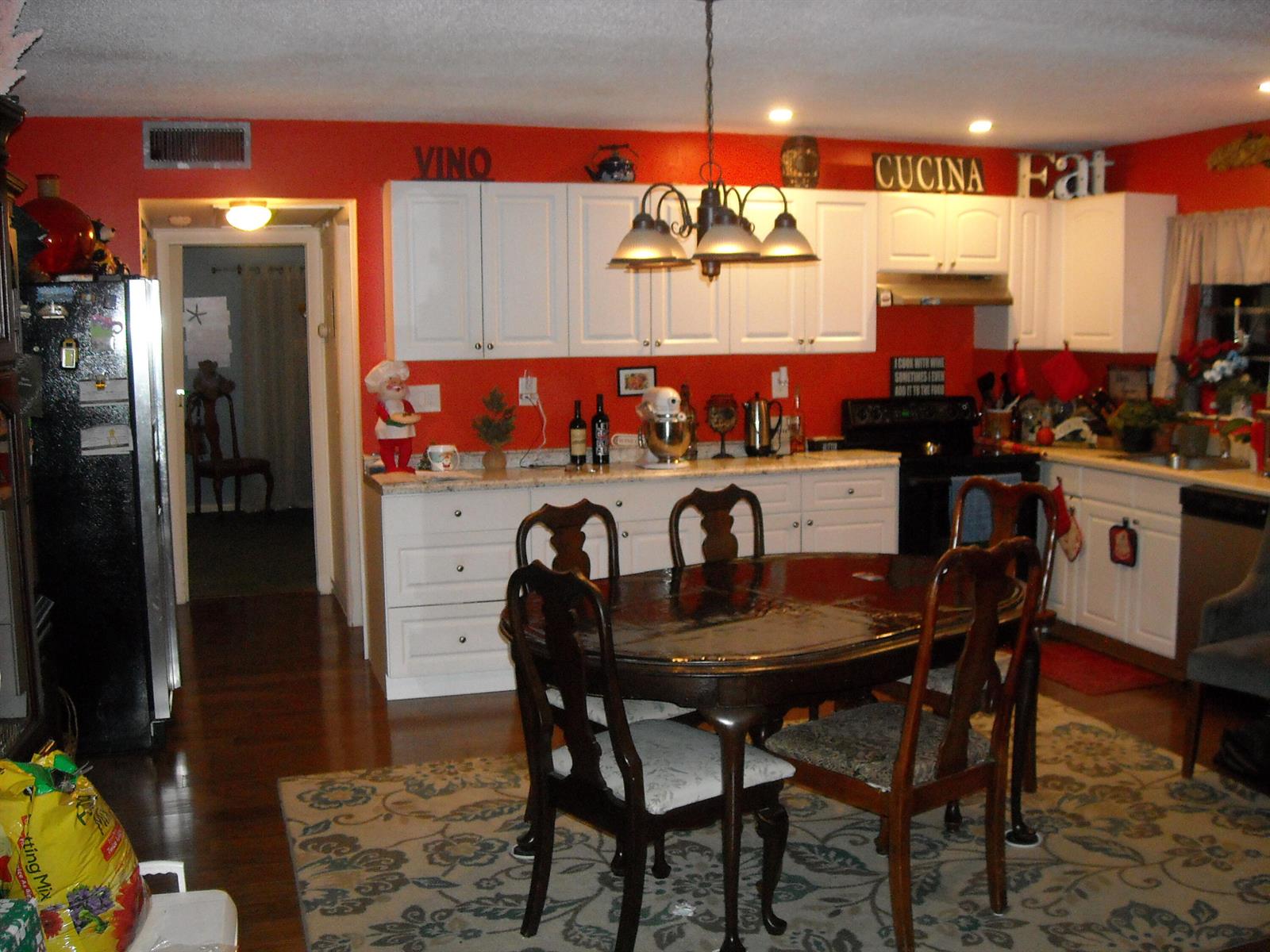 A kitchen with white cabinets, red walls, a dark wood dining table, and a patterned rug — 216 Sheffield I, West Palm Beach FL 33417, WEST PALM BEACH, FL