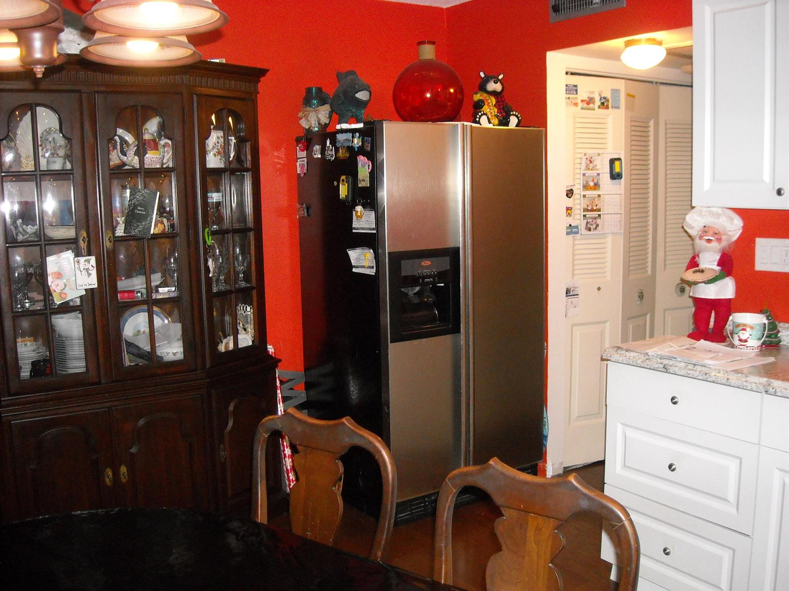 A dining room features a dark wood china cabinet, stainless steel refrigerator, and red walls — 216 Sheffield I, West Palm Beach FL 33417, WEST PALM BEACH, FL