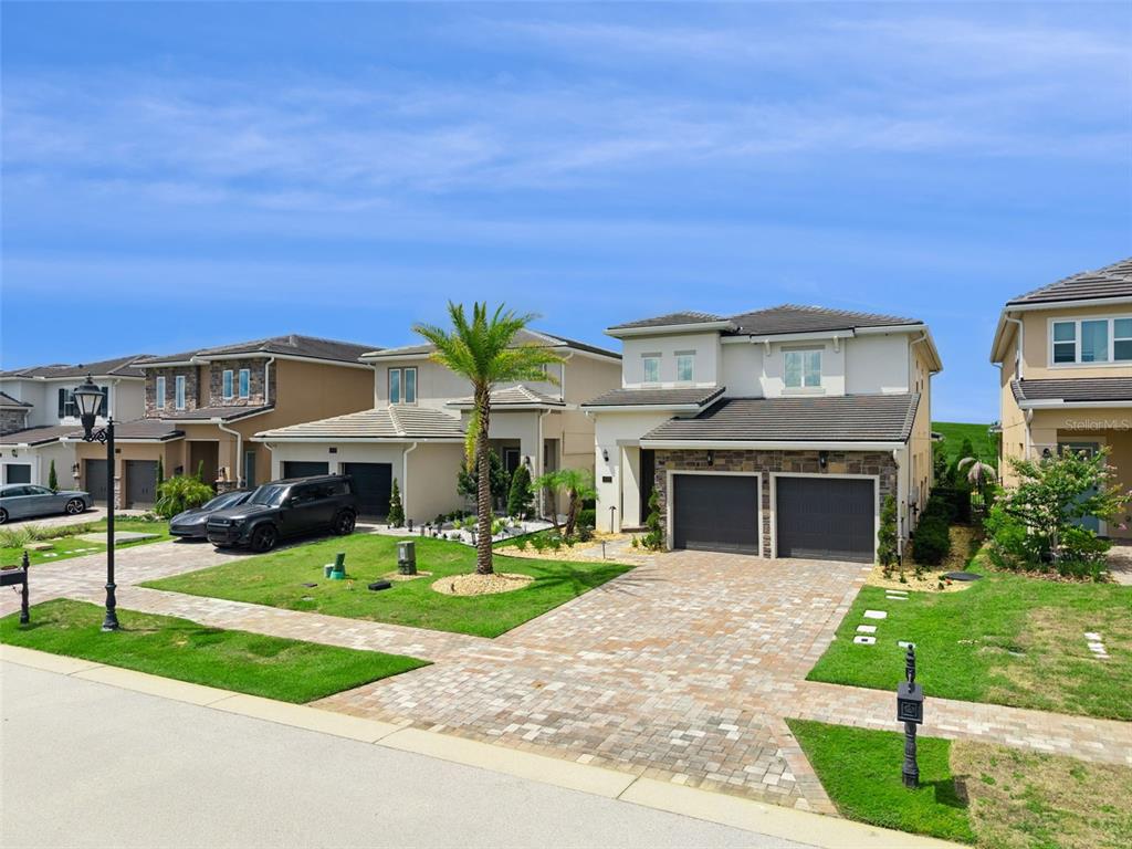 A street view of two-story suburban houses with paved driveways and green lawns — 15702 VETTA DRIVE, BELLA COLLINA, FL